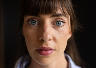 Close-up of woman with blue eyes and bangs, looking directly at camera