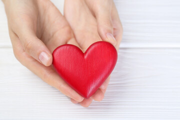 Obraz premium Woman holding red heart at white wooden table, closeup