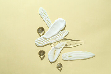 Smears of different cosmetic products on beige background, top view