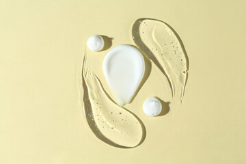 Smears of different cosmetic products on beige background, top view