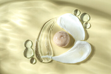 Smears of different cosmetic products on beige background, top view