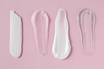 Smears of different cosmetic products on pink background, flat lay