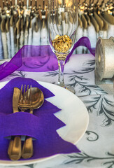 Detail of a festive table served with golden plates and glasses, Christmas or New Year's Eve.