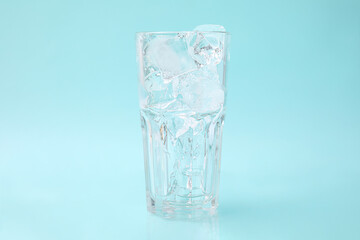 Refreshing water with ice cubes in glass on light blue background