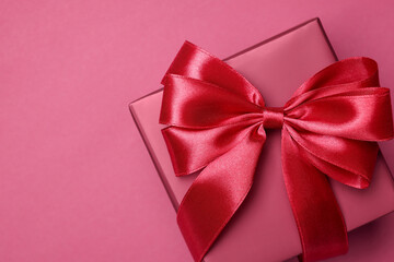 Gift box with bow on pink background, top view. Space for text