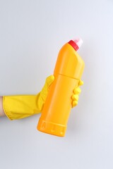 Woman holding toilet cleaner in bottle on light background, closeup