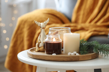 Burning candles, fir branches and decorative deer on coffee table indoors. Christmas atmosphere
