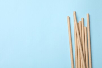 Bamboo drinking straws on light blue background, top view. Space for text