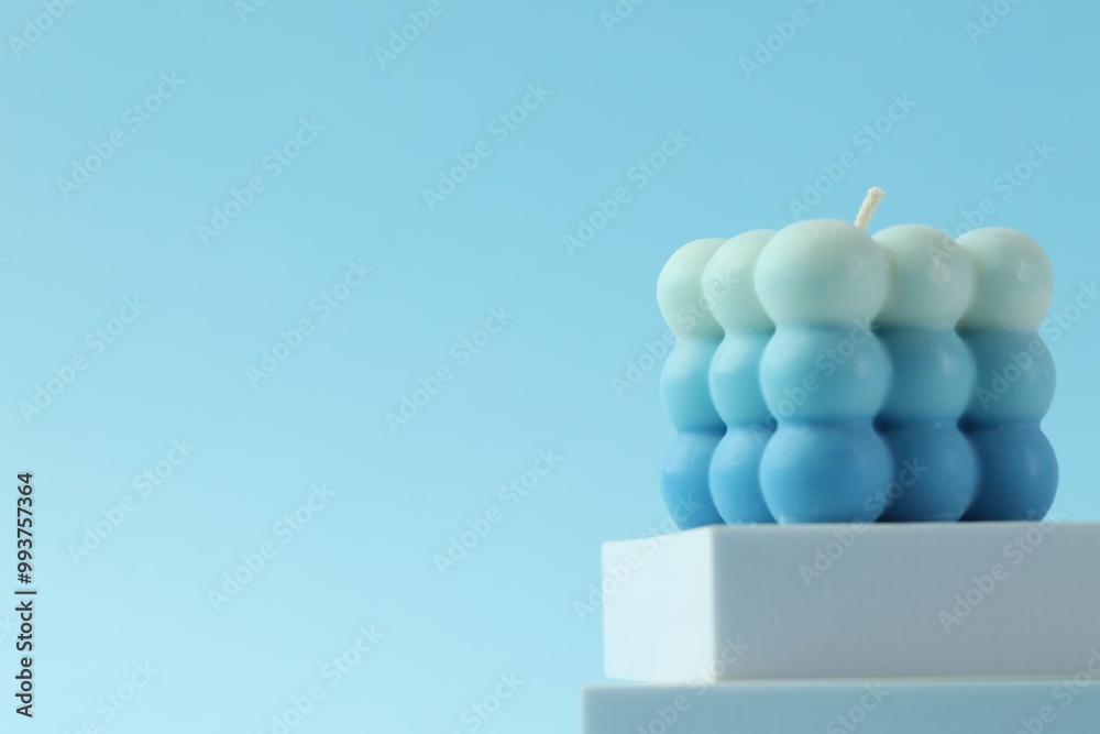 Canvas Prints Beautiful bubble candle and podium on light blue background, closeup. Space for text