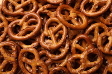 Many delicious pretzel crackers as background, top view