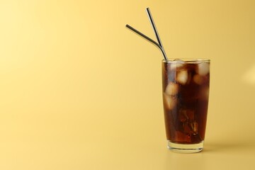 Tasty refreshing drink with straws in glass on beige background, space for text