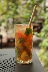 Glass of tasty refreshing drink and straw on table in outdoor cafe