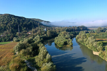 Aerial view of quiet river and forest in a misty morning