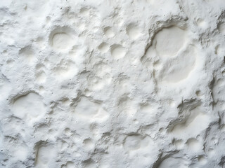 A close-up of a textured white surface with craters and indentations, resembling a lunar landscape...