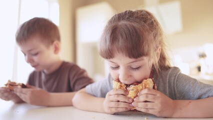 children eat burgers. fun fast food burger. a group of small children in the kitchen greedily eat...