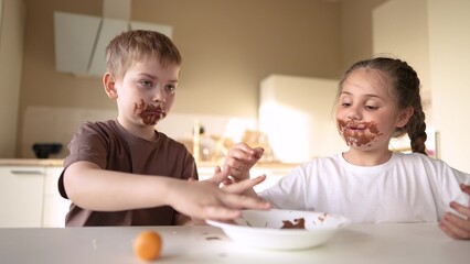baby boy and lifestyle girl eat chocolate. dirty little baby kids in the kitchen eating chocolate in the morning. happy family eating sweets kid dream concept. baby dirty face eating chocolate cocoa