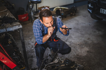 mechanic inspect car engine with tool at garage and record voice mail