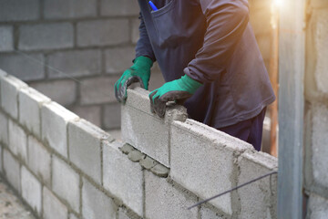 masonry worker make concrete wall by cement block and plaster at construction site