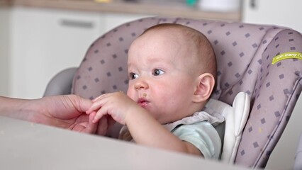 baby boy eats lunch at a feeding table in the kitchen. happy family child dream concept. mother feeds the baby in the kitchen. Baby child eats lunch in the kitchen lifestyle