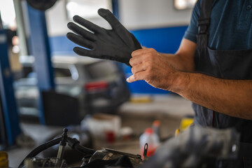 Car mechanic wear gloves preparing to work on vehicle engine