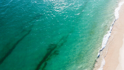 Aerial view of the beautiful turquoise sea with algae in Comporta, Portugal