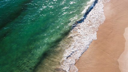 Aerial view of the beautiful turquoise sea with algae in Comporta, Portugal
