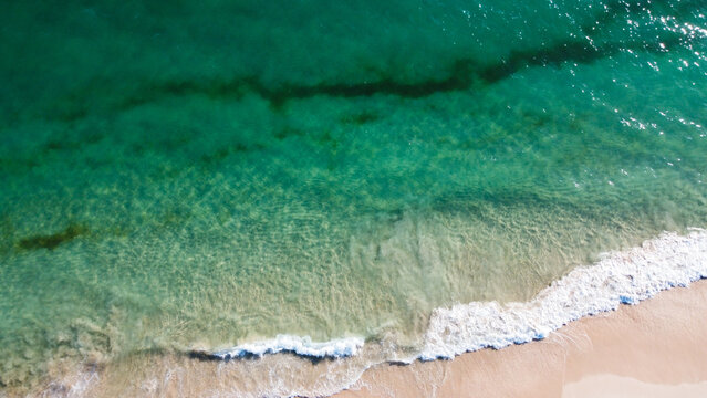 Aerial view of the beautiful turquoise sea with algae in Comporta, Portugal