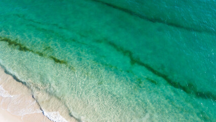 Aerial view of the beautiful turquoise sea with algae in Comporta, Portugal