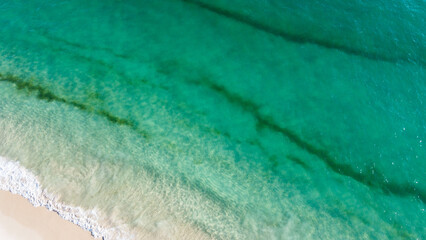 Aerial view of the beautiful turquoise sea with algae in Comporta, Portugal