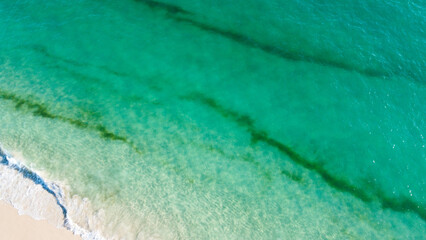 Aerial view of the beautiful turquoise sea with algae in Comporta, Portugal