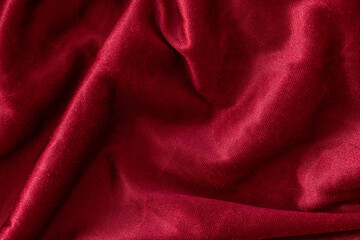 Red velvet textile folded fabric for background. Top view.