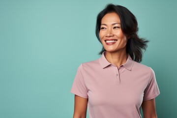 Fototapeta premium Portrait of a smiling asian woman in her 40s wearing a sporty polo shirt in front of pastel or soft colors background