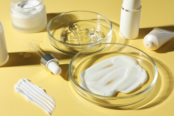 Petri dishes with cosmetic products and pipette on yellow background, closeup