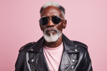 Obraz premium Portrait of a glad afro-american man in his 60s sporting a classic leather jacket on pastel or soft colors background