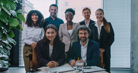 Portait multi-ethnic group of people gathering together behind table. Looking directly at camera while smiling. Growing business. Team building.