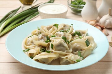 Delicious pelmeni with green onion served on white wooden table, closeup