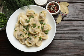 Delicious pelmeni with green onion served on wooden table, flat lay
