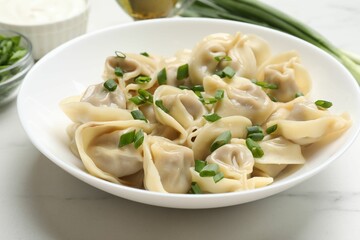 Delicious pelmeni with green onion on white table, closeup