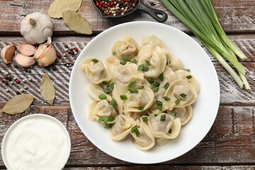 Delicious pelmeni with green onion served on wooden table, flat lay