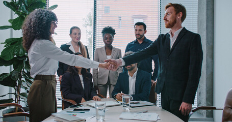 Female and male shaking their hands. Standing in front of group of consultants. Everyone clapping....