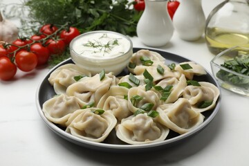 Delicious pelmeni with green onion served on white marble table, closeup