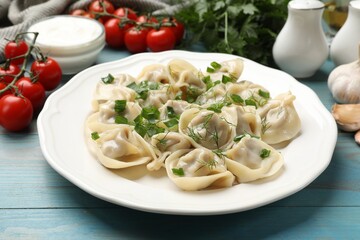 Delicious pelmeni with green onion served on blue wooden table