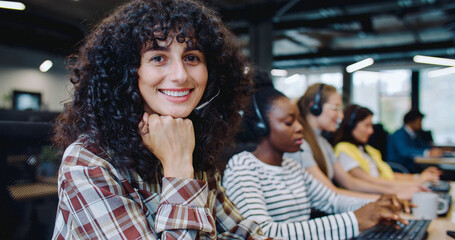 Consultants supporting their clients from office. Women using headset while remotely talking into microphones. Typing text on computers during communication. Call center concept.