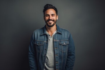 Obraz premium Portrait of a happy man in his 30s sporting a rugged denim jacket isolated on minimalist or empty room background