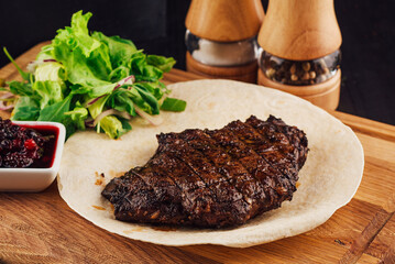 Grilled beef steak with berry sauce and fresh salad served on a white plate
