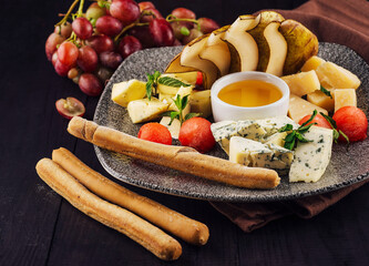 Gourmet cheese plate offering variety of textures and flavors with honey and grapes