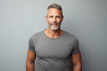 Fototapeta premium Portrait of a glad man in his 40s donning a trendy cropped top while standing against minimalist or empty room background