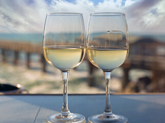 Cheers - Two Wine glasses side by side with an out of focus view of Pier and ocean