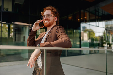 A fashionable businessman is engrossed in a phone call outside a sleek and modern contemporary...
