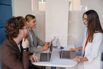 In a modern office environment, various professionals are collaboratively working together on their laptops